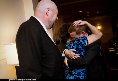 Erica and Rob hug while her husband Mike waits for his turn