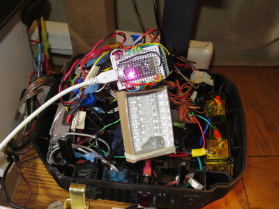 Here is the ItsyBitsy M4 out of the cradle. The informative NeoPixel was hard to see, so I lined the cradle with reflective wrapping paper. There is a clear plastic layer to prevent any metal in the shiny paper from causing a short.